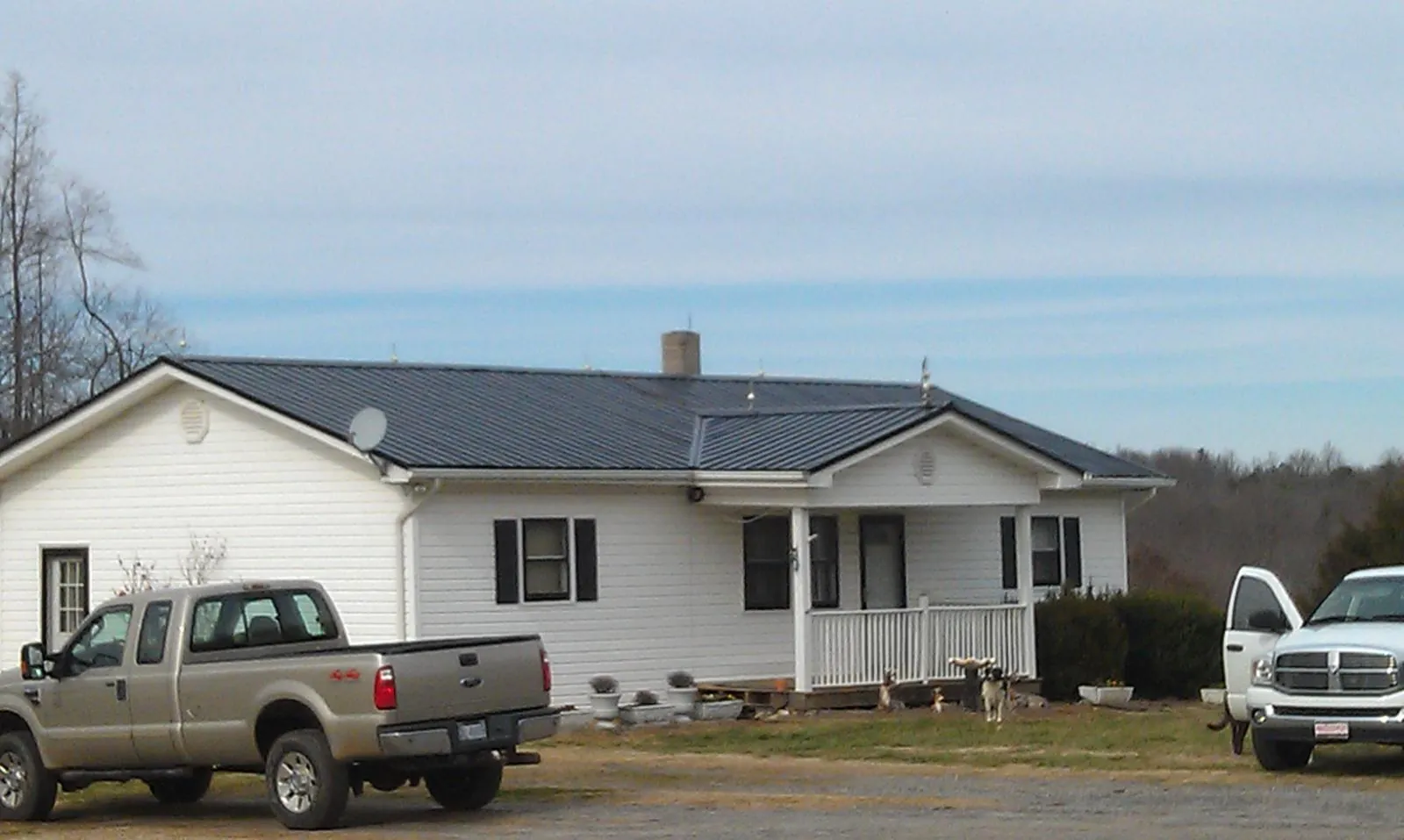 Finished dark metal roof on a white ranch home with work trucks parked in Uniontown