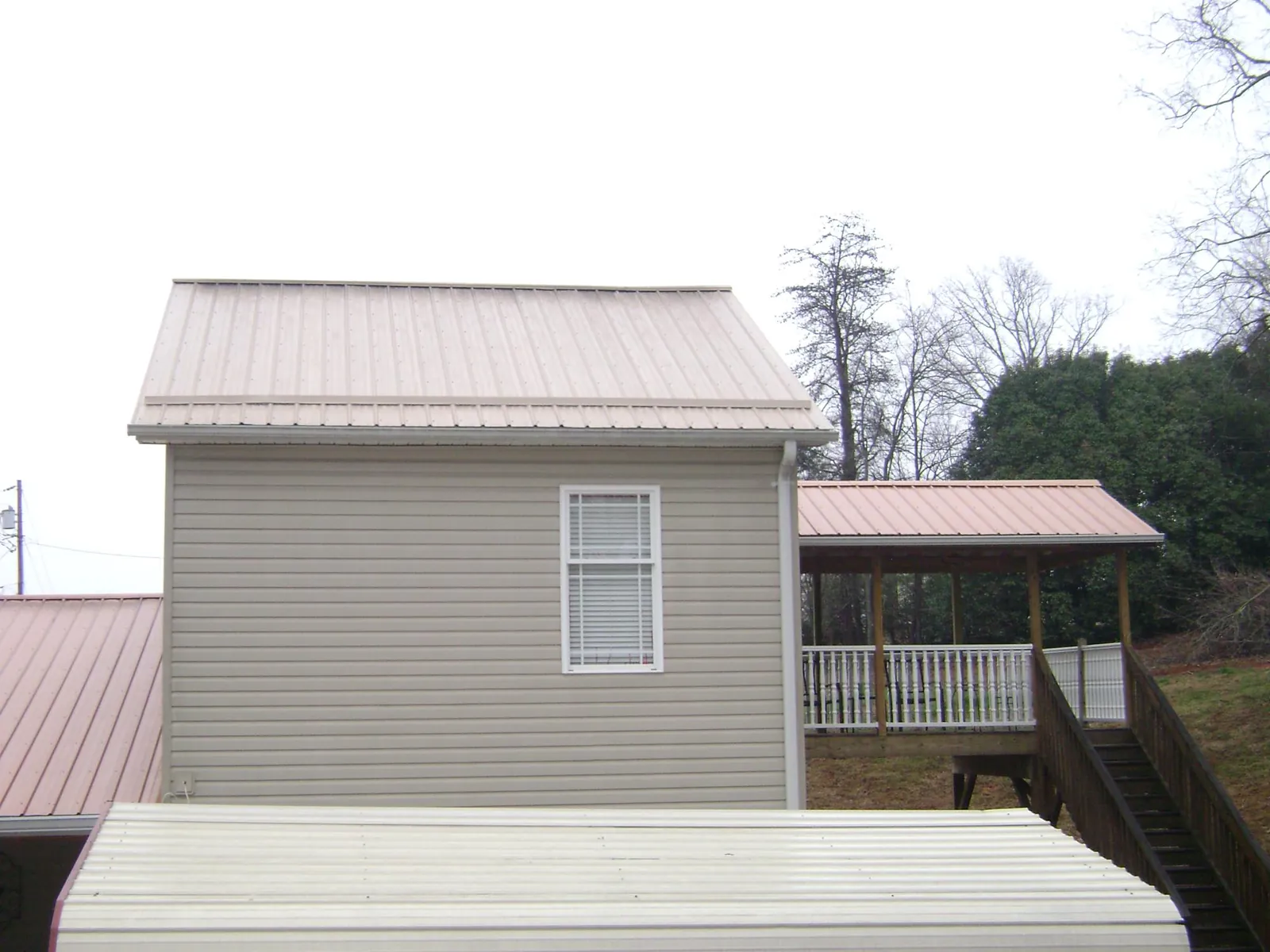 Tan metal roofs on a two story addition and attached porch, from a Roof Replacement job in Uniontown